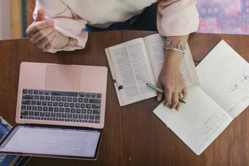 Kate making space for her first draft via notebooks and a new document on her laptop