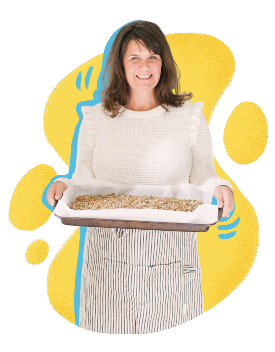 Kate Wallace holding up a baking sheet, wearing an apron